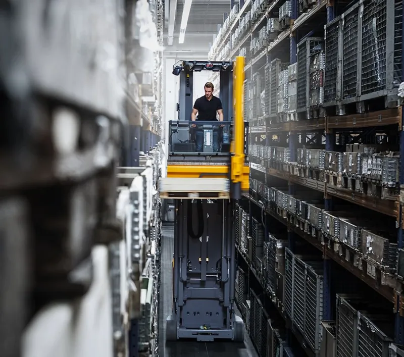 Man operating forklift in a very narrow aisle in a warehouse